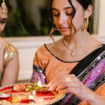 Mother and daughter performing a Diwali ritual with a lit puja plate, showcasing traditional Indian culture.