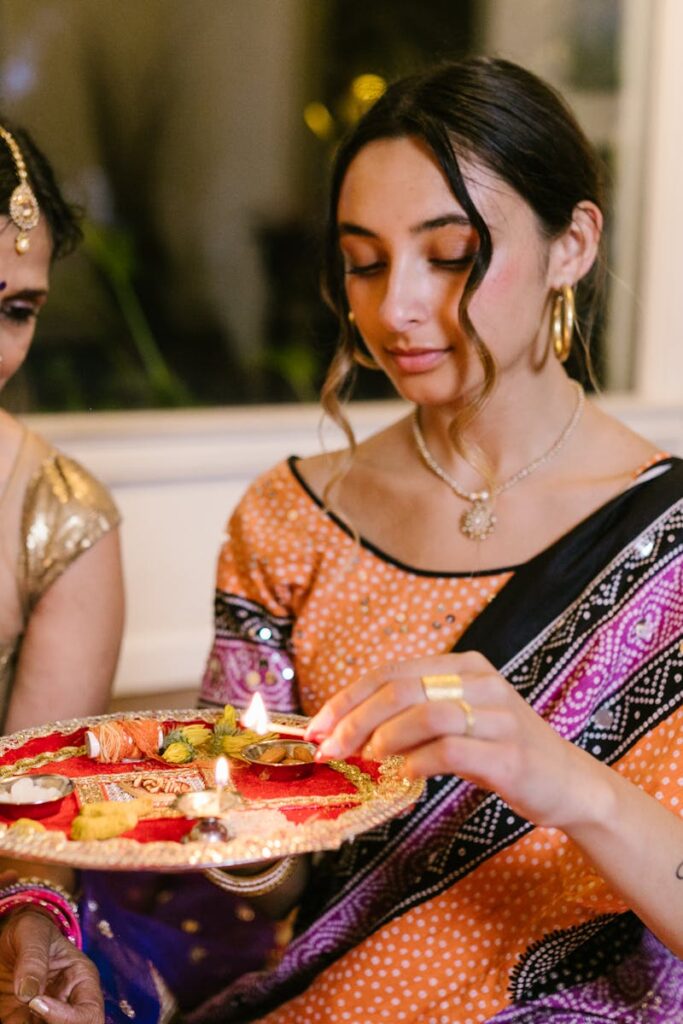 Mother and daughter performing a Diwali ritual with a lit puja plate, showcasing traditional Indian culture.